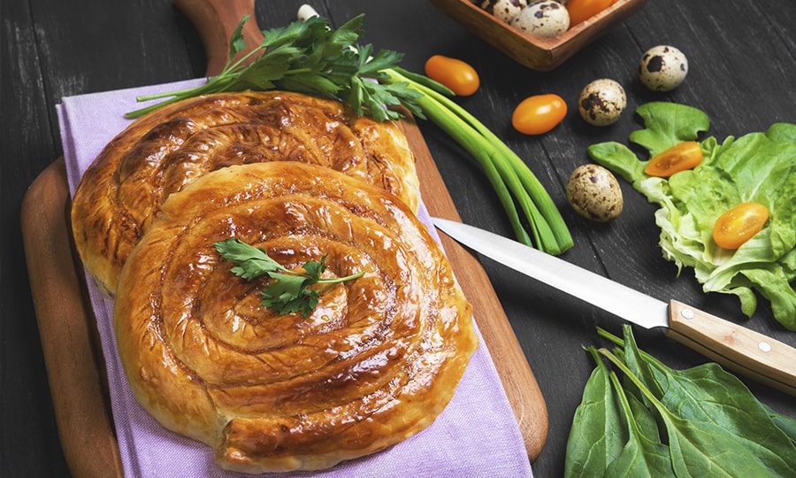 Традиционна българска трапеза с разнообразие от автентични ястия, поднесени на дървена маса с етнографски елементи